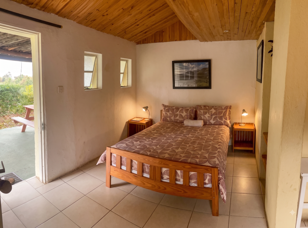Cottage 2 bedroom at Heaven Lodge Chimanimani with double bed, timber ceiling, and door opening to outdoor patio